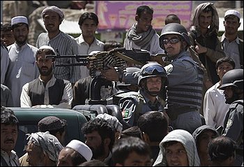 Afghan police ride in a truck past a crowd that gathered near the scene of a gunbattle with suspected insurgents in Kabul, Wednesday, Aug. 19, 2009. Gunfire and explosions reverberated through the heart of the Afghan capital Wednesday on the eve of the presidential election after three militants with AK-47s rifles and hand grenades overran a bank. Police stormed the building and killed the three insurgents, officials said. (AP Photo/Kevin Frayer)